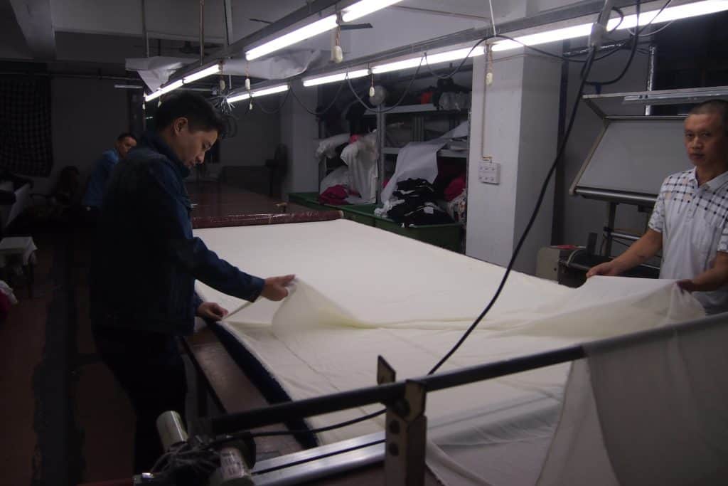 Workers laying fabric on cutting table