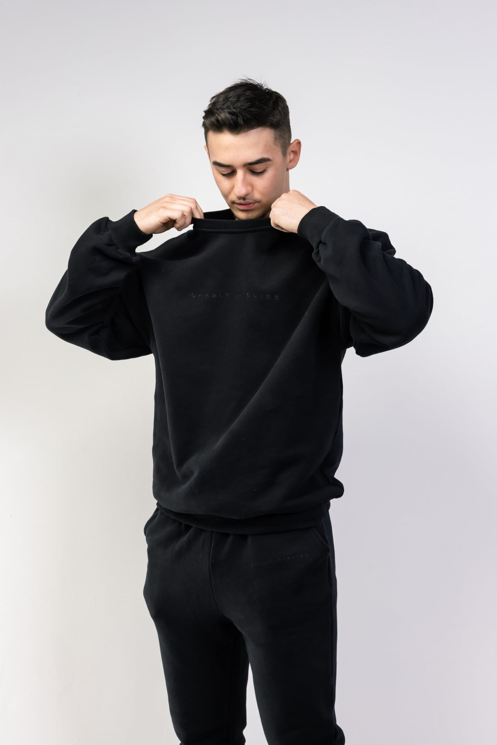 Young man wearing black streetwear hoodie and sweatpants.